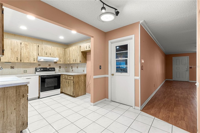 kitchen with electric range oven, decorative backsplash, sink, light tile patterned flooring, and a textured ceiling