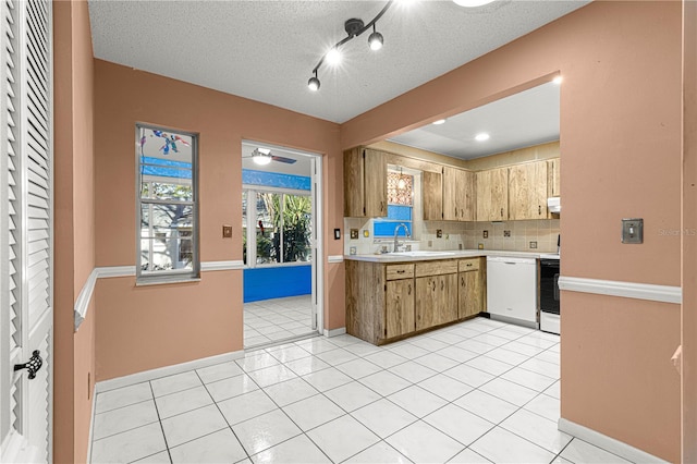 kitchen with sink, light tile patterned floors, dishwasher, and tasteful backsplash