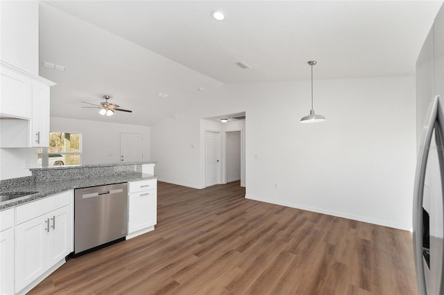 kitchen with stainless steel dishwasher, vaulted ceiling, dark hardwood / wood-style floors, white cabinets, and dark stone counters