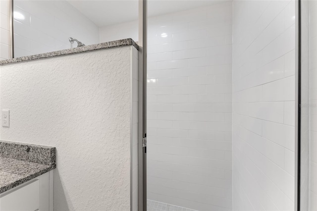 bathroom featuring a tile shower and vanity