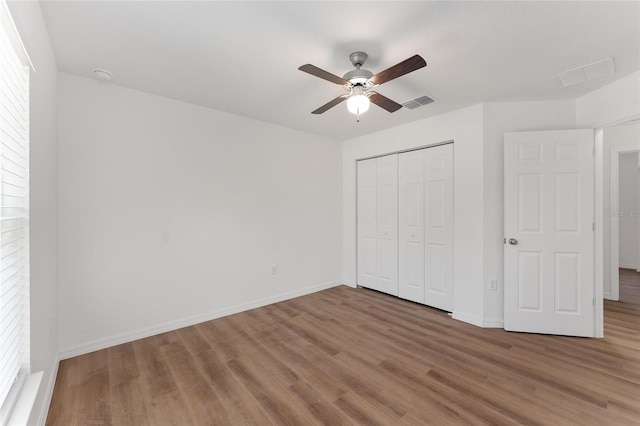 unfurnished bedroom with ceiling fan, a closet, and wood-type flooring