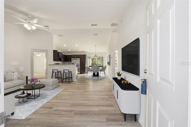 living room with light hardwood / wood-style flooring, vaulted ceiling, and ceiling fan