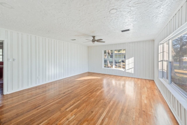 spare room with ceiling fan, light hardwood / wood-style flooring, and a textured ceiling