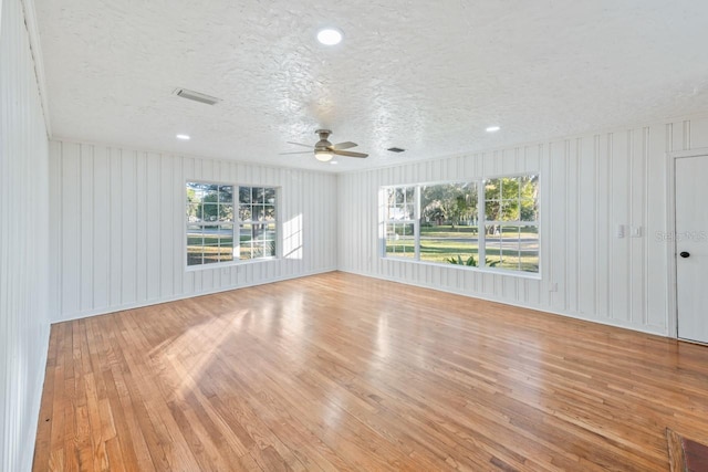 spare room featuring light hardwood / wood-style floors, ceiling fan, and a textured ceiling