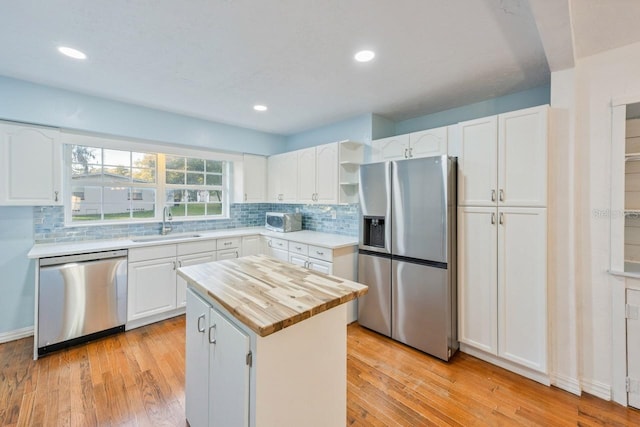 kitchen with a kitchen island, stainless steel appliances, white cabinets, and sink