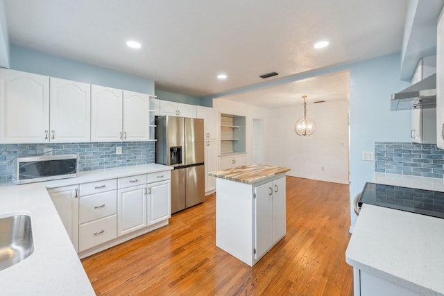 kitchen with hanging light fixtures, stainless steel appliances, tasteful backsplash, a kitchen island, and white cabinetry