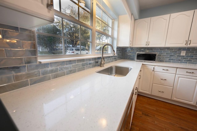 kitchen with sink, white cabinetry, and light stone counters