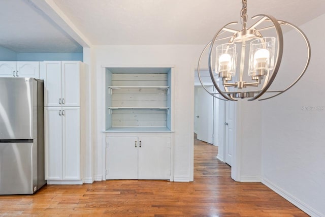 unfurnished dining area with a notable chandelier and light hardwood / wood-style flooring