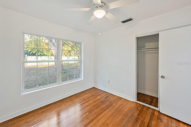 unfurnished bedroom with hardwood / wood-style flooring, ceiling fan, and a closet