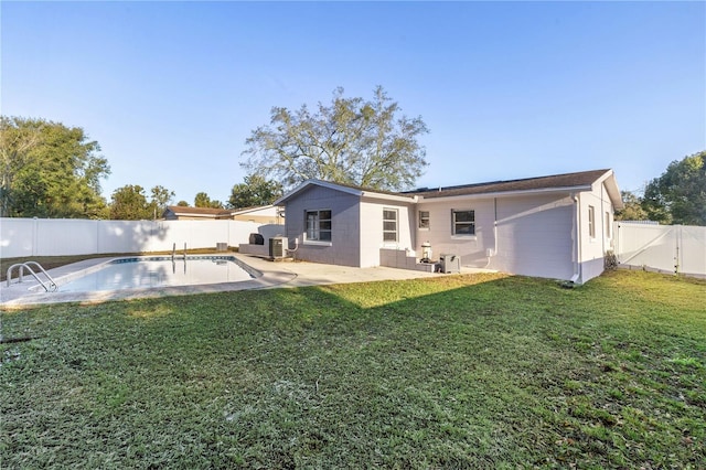 back of property with a patio area, a lawn, and a fenced in pool