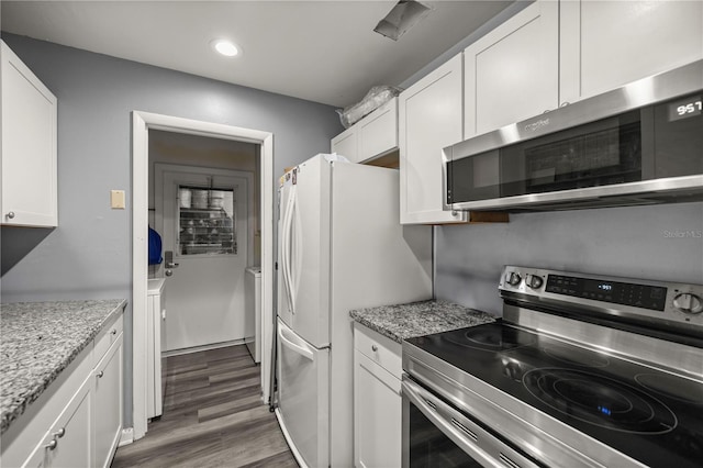 kitchen with appliances with stainless steel finishes, dark hardwood / wood-style flooring, white cabinets, and light stone counters