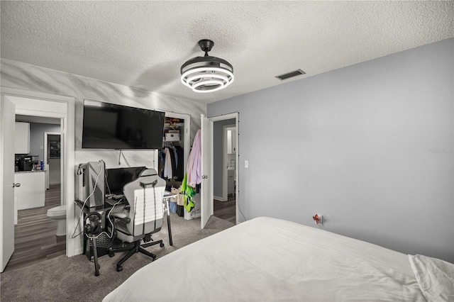 bedroom featuring a textured ceiling, a closet, ensuite bath, and carpet flooring