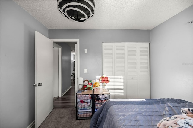 bedroom with a closet, a textured ceiling, and dark colored carpet