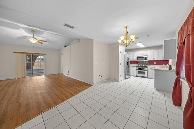 unfurnished living room with sink, light tile patterned flooring, and ceiling fan with notable chandelier