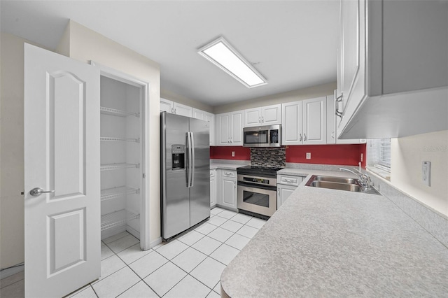 kitchen with appliances with stainless steel finishes, white cabinetry, backsplash, and sink