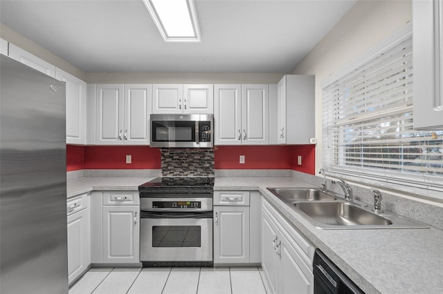 kitchen with stainless steel appliances, light tile patterned floors, white cabinets, and sink