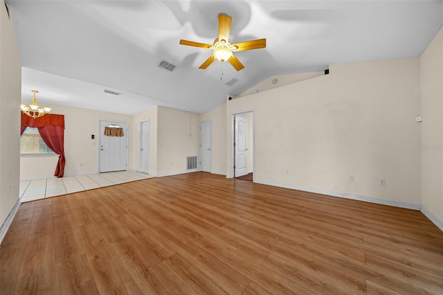 unfurnished living room with ceiling fan with notable chandelier, vaulted ceiling, and light hardwood / wood-style flooring