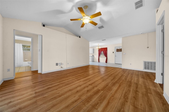 unfurnished living room with ceiling fan with notable chandelier, light wood-type flooring, and vaulted ceiling