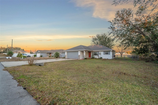 ranch-style home with a garage and a lawn