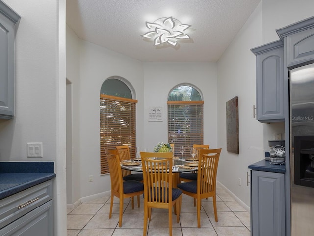 tiled dining room with a textured ceiling and a notable chandelier