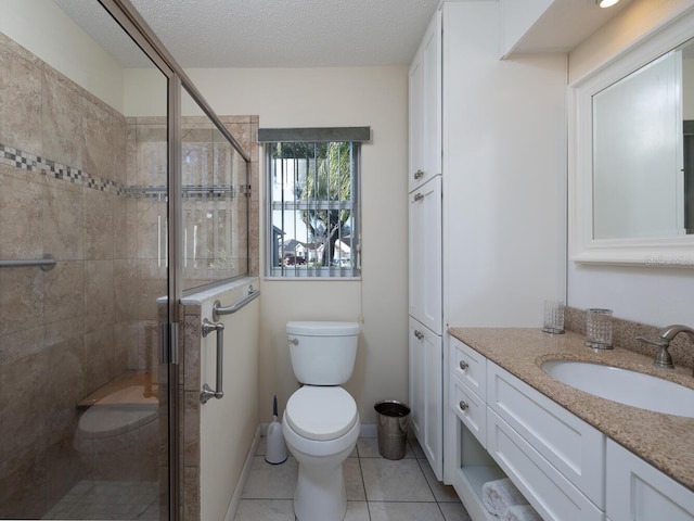 bathroom with toilet, vanity, tile patterned floors, a shower with door, and a textured ceiling