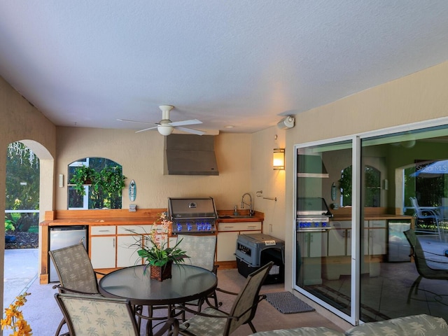 view of patio featuring exterior kitchen, sink, ceiling fan, and area for grilling