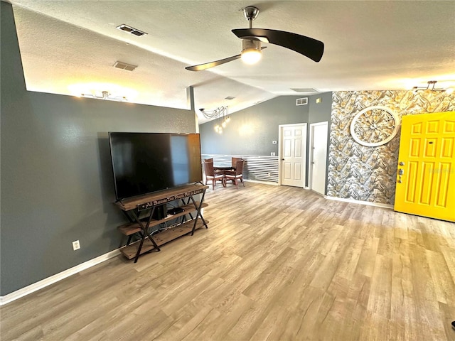 living room with wood-type flooring, a textured ceiling, ceiling fan, and vaulted ceiling