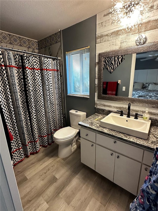 bathroom with toilet, a textured ceiling, wood-type flooring, and vanity