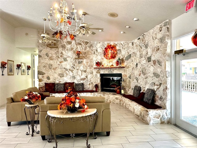 living room featuring ceiling fan with notable chandelier, a fireplace, and a textured ceiling