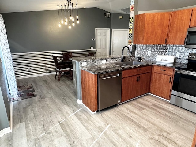 kitchen featuring stainless steel appliances, light wood-type flooring, kitchen peninsula, pendant lighting, and sink