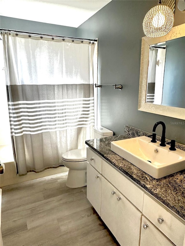 full bathroom with hardwood / wood-style floors, shower / bath combination with curtain, vanity, and toilet