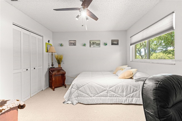 bedroom featuring a textured ceiling, ceiling fan, a closet, and carpet floors