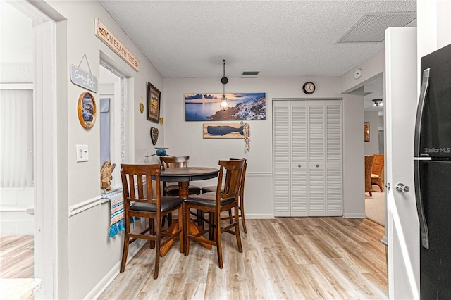 dining area featuring a textured ceiling and light wood-type flooring