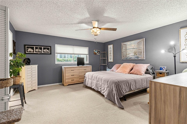 bedroom featuring ceiling fan, light carpet, and a textured ceiling