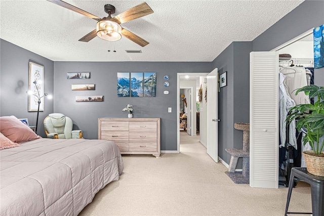 carpeted bedroom featuring ceiling fan, a closet, and a textured ceiling