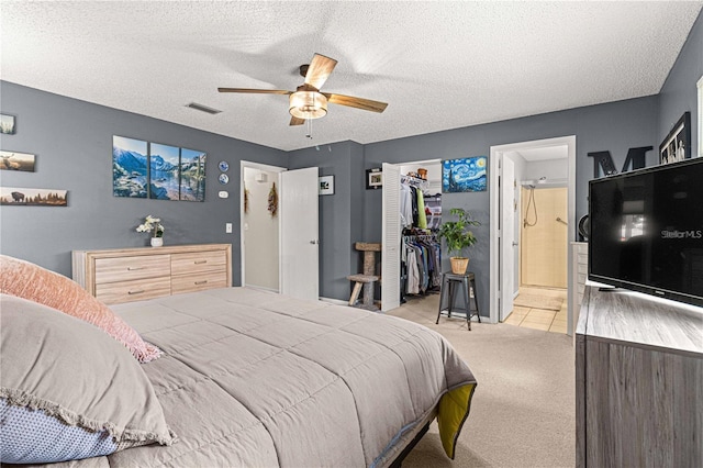 bedroom with ensuite bathroom, ceiling fan, a closet, light colored carpet, and a textured ceiling