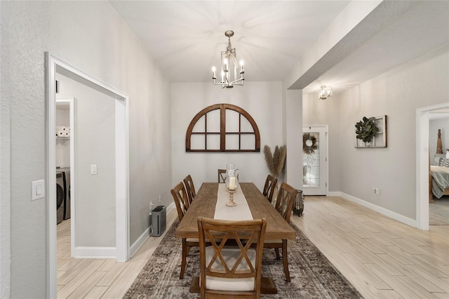 dining room with washer / clothes dryer, a notable chandelier, and light hardwood / wood-style flooring