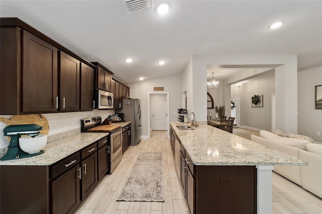 kitchen with a chandelier, appliances with stainless steel finishes, light stone counters, dark brown cabinetry, and sink