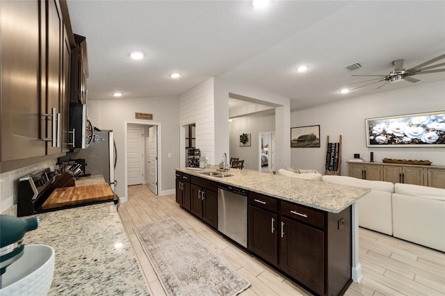 kitchen with light stone counters, sink, stainless steel appliances, ceiling fan, and dark brown cabinetry