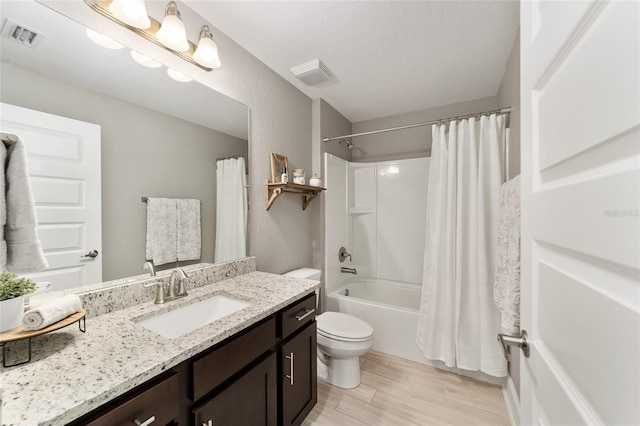 full bathroom with a textured ceiling, hardwood / wood-style flooring, toilet, shower / bath combination with curtain, and vanity