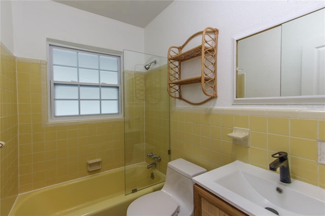 full bathroom with toilet, vanity, tile walls, and tiled shower / bath combo