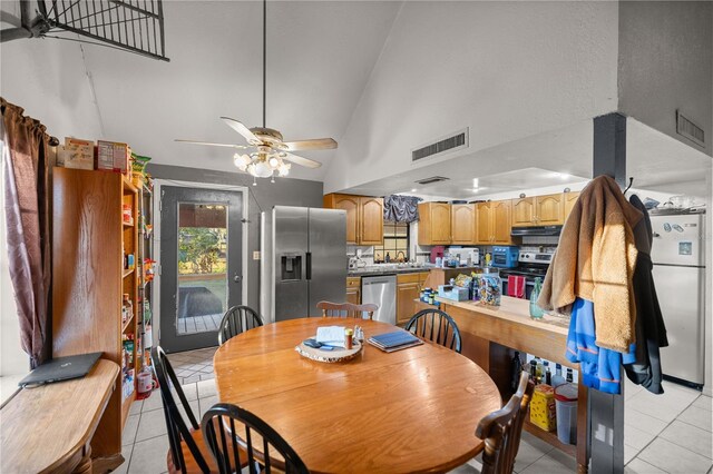 tiled dining area with high vaulted ceiling and ceiling fan