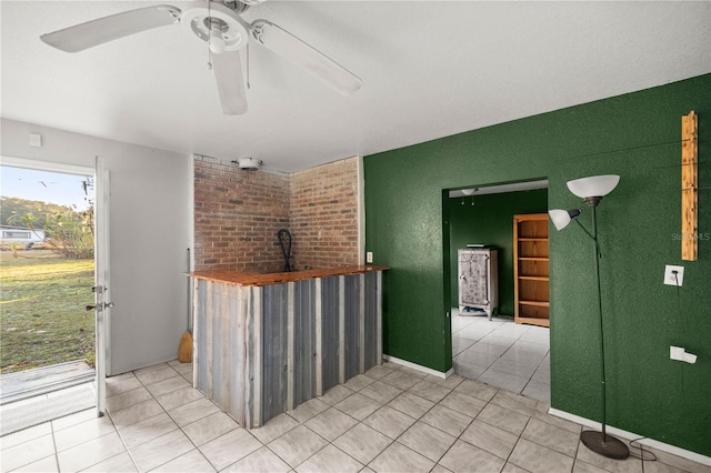 kitchen featuring ceiling fan, butcher block countertops, a wood stove, and light tile patterned floors