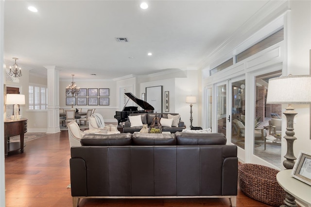 living room with ornate columns, ornamental molding, dark wood-type flooring, and a chandelier