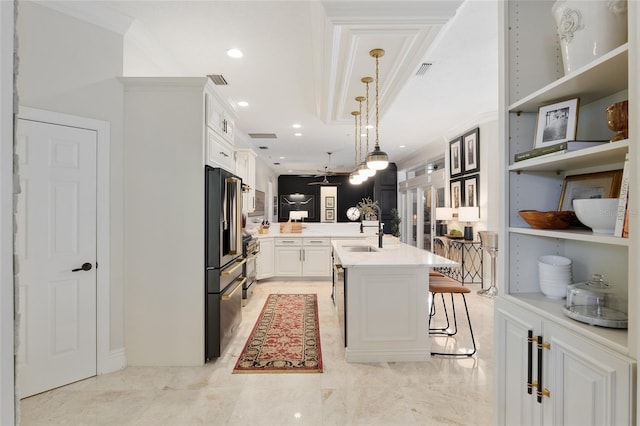 kitchen featuring white cabinetry, decorative light fixtures, a center island with sink, appliances with stainless steel finishes, and a kitchen breakfast bar