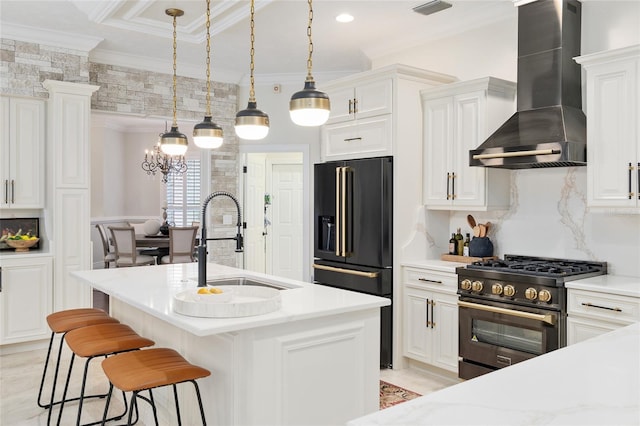 kitchen with high end appliances, wall chimney range hood, and white cabinets