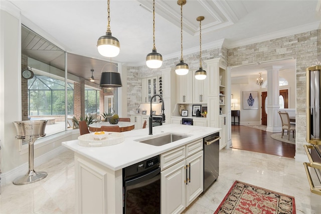 kitchen featuring sink, white cabinetry, a kitchen island with sink, ornamental molding, and decorative light fixtures