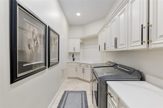 laundry area with cabinets, washer and clothes dryer, and sink