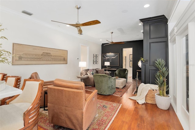 living room featuring crown molding, wood-type flooring, and ceiling fan