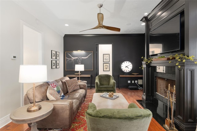 living room with wood-type flooring, crown molding, and ceiling fan